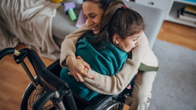 niña en silla de ruedas abrazada por su madre