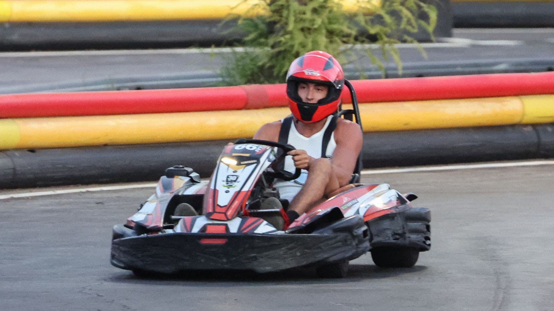 Plex en kart rojo y blanco, con casco rojo, en pista de carreras.