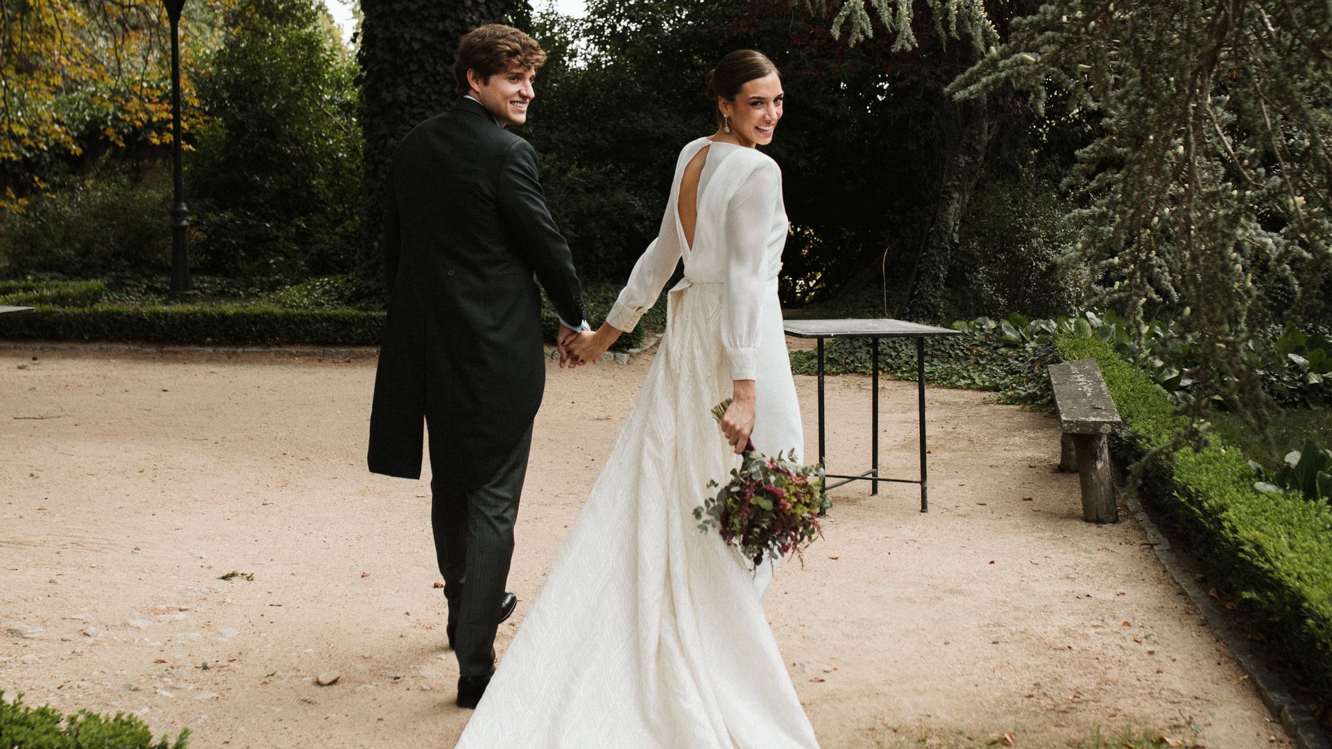 La boda de Bea y Gregorio en Madrid: un vestido de novia con camisa de organza, unos pendientes desmontables y un ramo en tonos burdeos