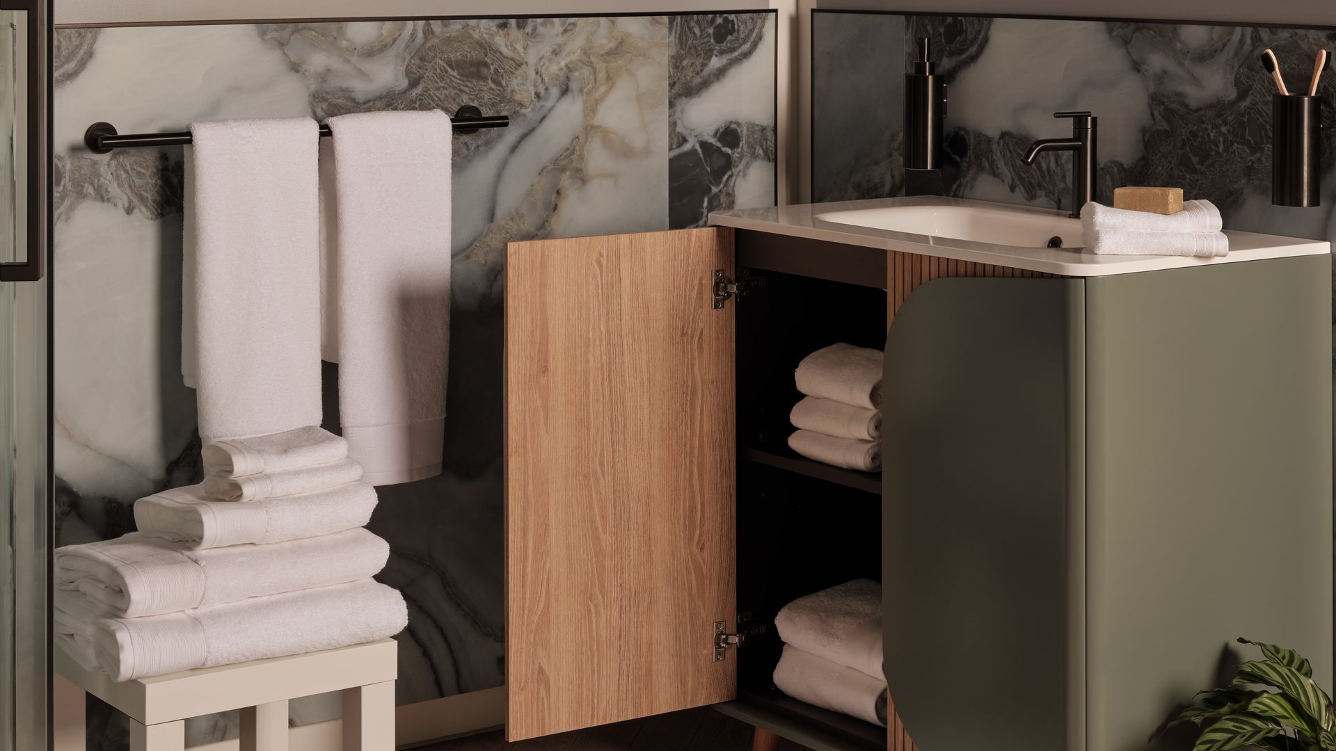 Baño con zócalo alto, paredes grises, mueble de lavabo verde, espejo ovalado, toallas blancas, lámina en la pared