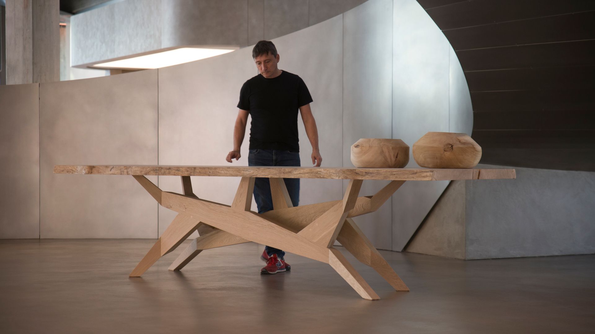 El ebanista Xavier Max delante de una mesa de comedor de madera hecha a mano