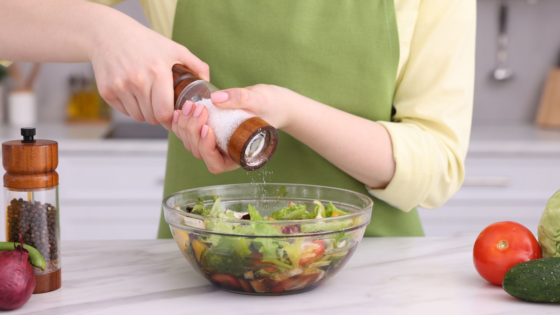 Mujer echando sal en una ensalada