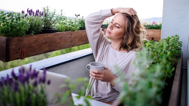 mujer cansada en la terraza de su casa, tomándose una infusión