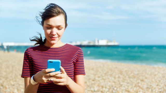 Mujer usando un móvil en la playa