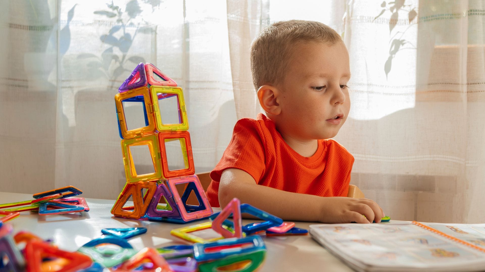 Niño consultando libro de instrucciones para usar imanes de construcción