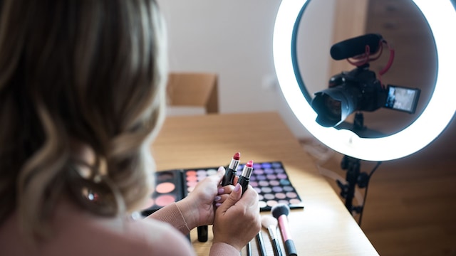 Una chica enseñando productos de belleza a una cámara con un aro de luz