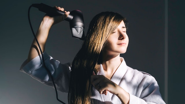 Una mujer secándose el pelo