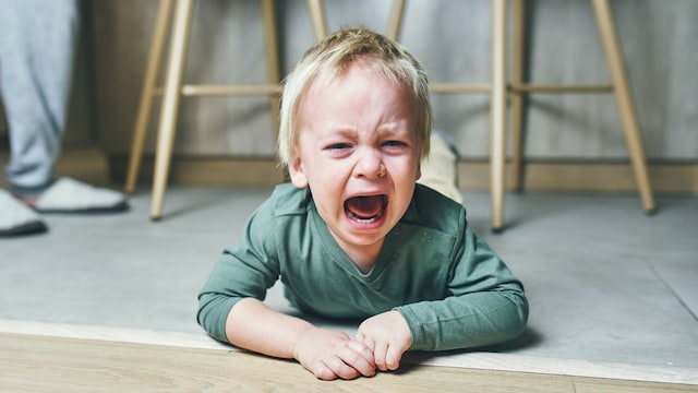 Niño pequeño tirado en el suelo en medio de una rabieta