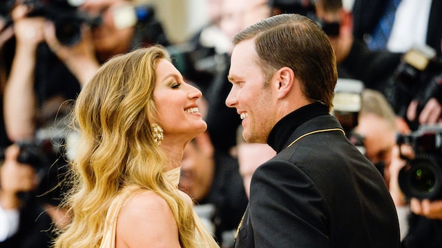 Plano medio de Tom Brady y Gisele Bündchen en un evento mirándose y sonriendo