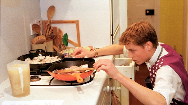 El príncipe William de Inglaterra cocinando una paella de pollo durante una clase de cocina en Eton.