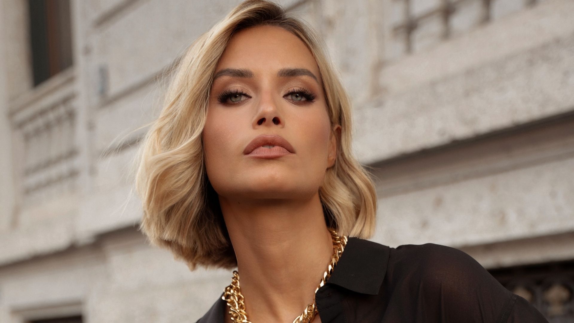 Giulia Arena con blusa y falda negra, collar metalizado y pelo corto rubio