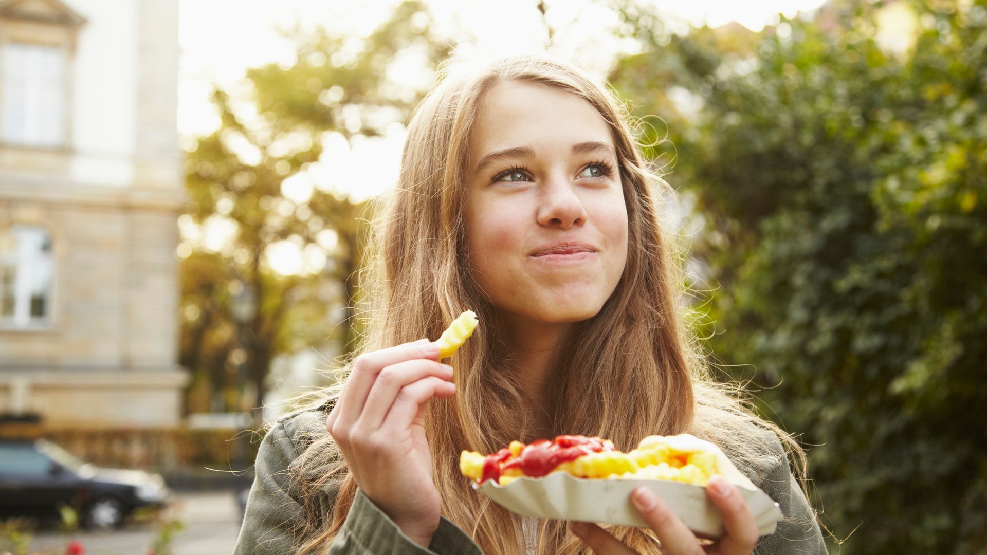 adolescente comiendo patatas fritas en la calle