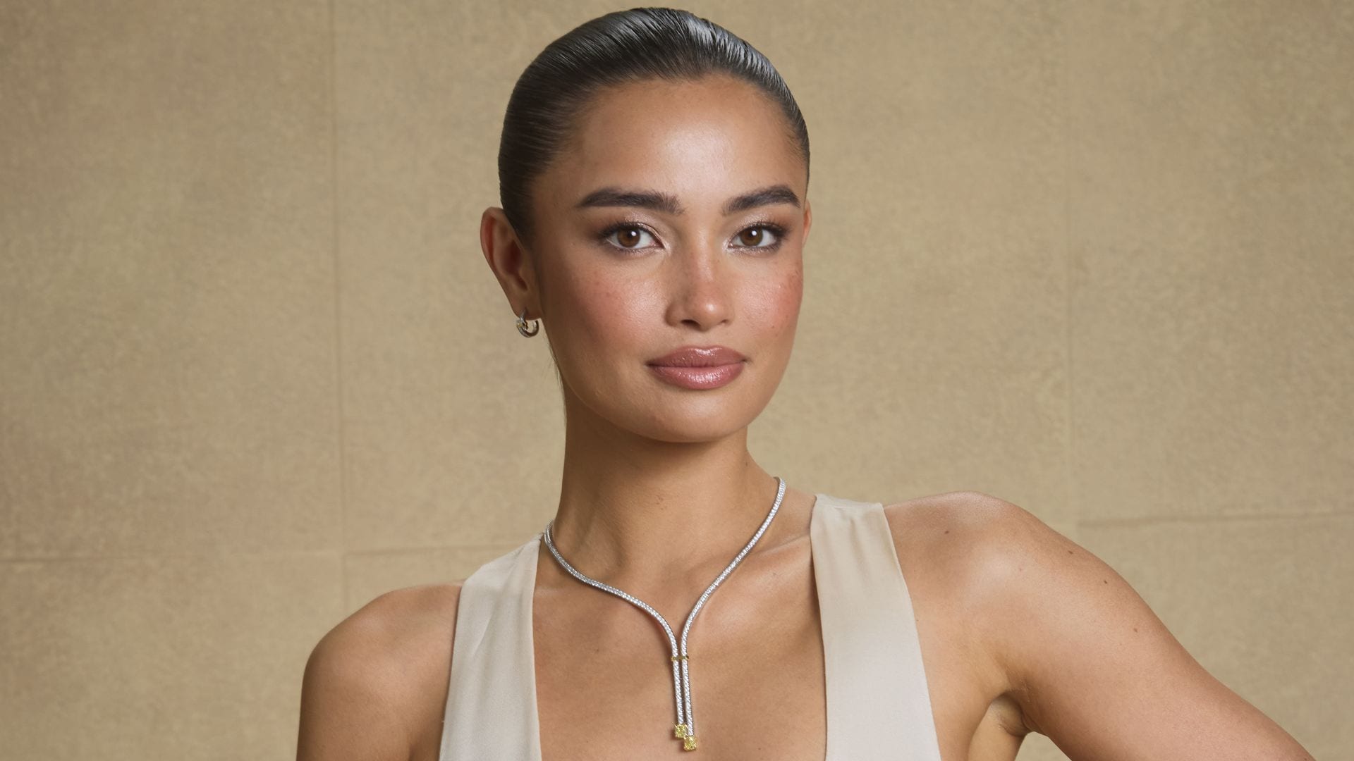 Kelsey Merrit en los Globos de Oro con vestido blanco perla de tejido satinado