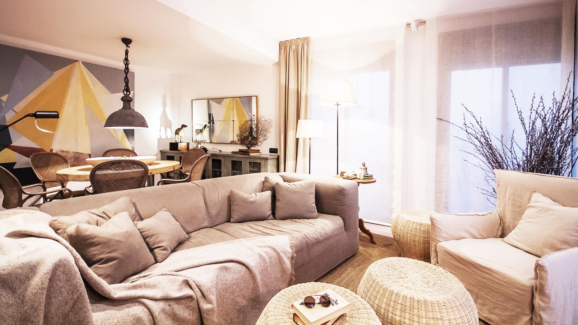 Salón comedor con cuadro, decorado en tonos beiges y fibras naturales, con sillón con funda, mesas de centro de fibras naturales