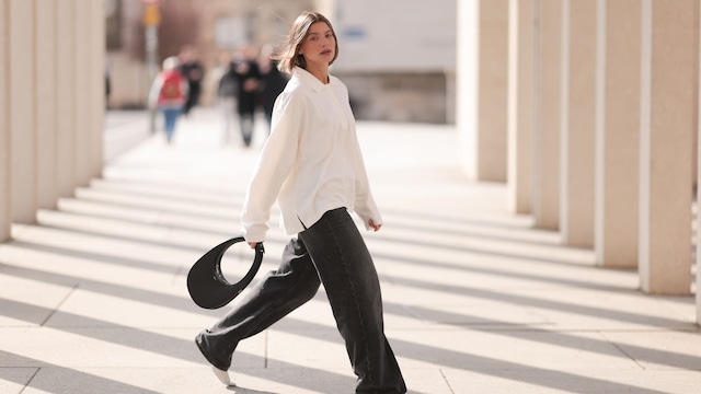 Sophia Geiss con pantalones vaqueros negros, camisa blanca y bolso de mano en Berlin