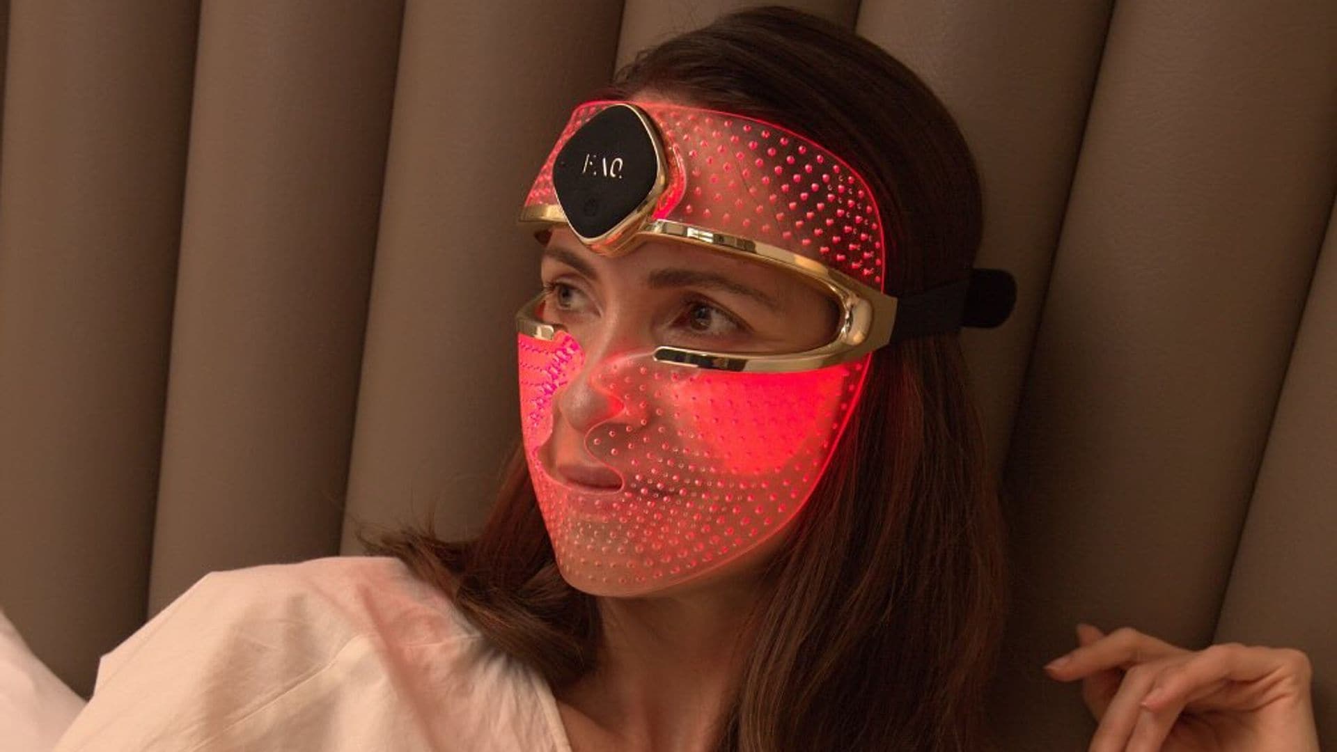 Mujer sentada en su cama con máscara LED de FOREO puesta