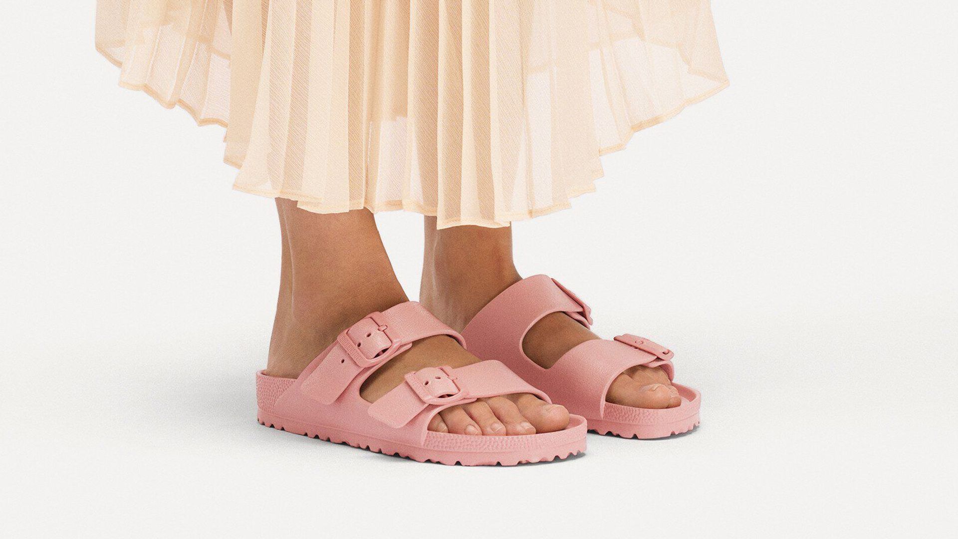 Mujer con sandalias Birkenstock EVA rosas y falda plisada color mantequilla