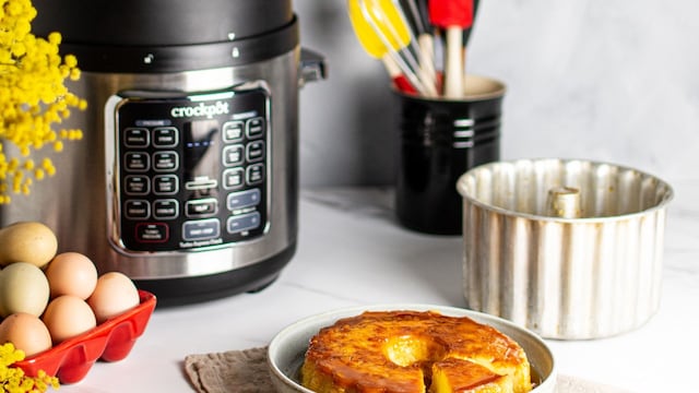 Olla de cocción lenta Crockpot con una receta de flan sobre una mesa, además de otros moldes, ingredientes y herramientas.