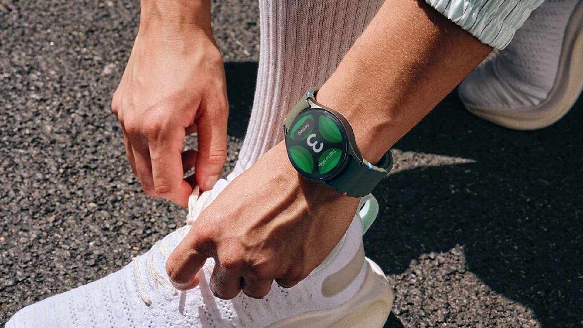 Mujer abrochándose los cordones de las zapatillas con reloj Samsung