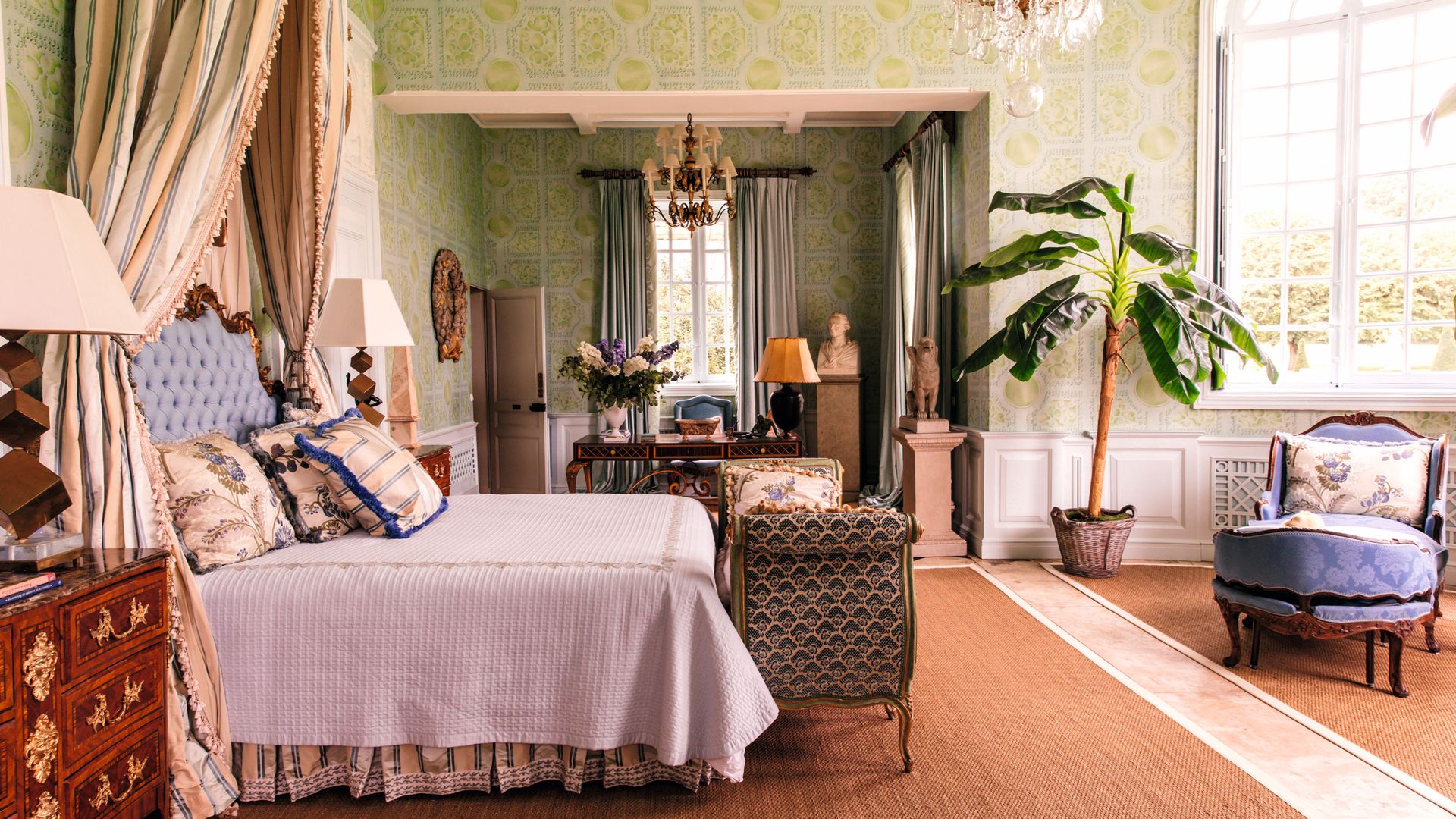 Habitación dormitorio con cama grande, sillas, plantas y ventanas