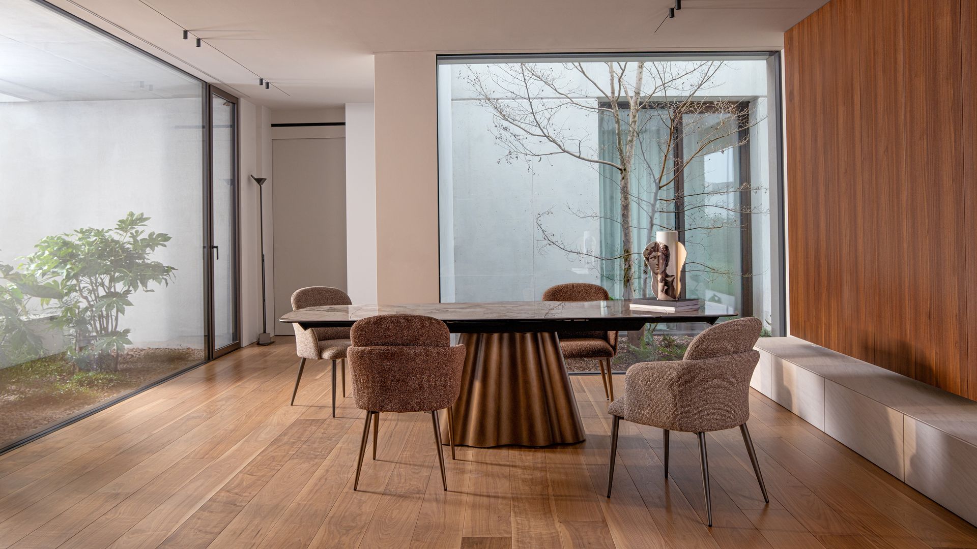 Comedor con mesa ovalada, sillas tapizadas, ventanal con vistas patio y pared de madera