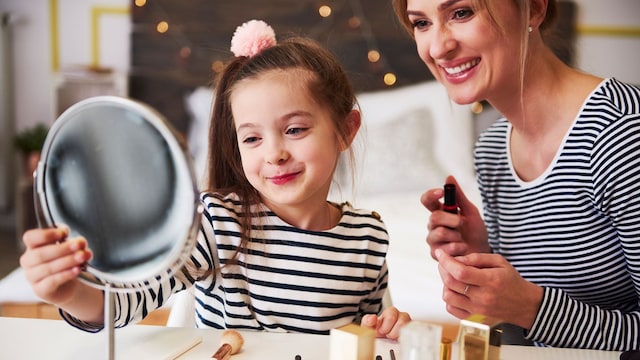 Niña se mira al espejo acompañada de su madre