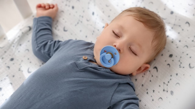 Bebé durmiendo con chupete en su cuna