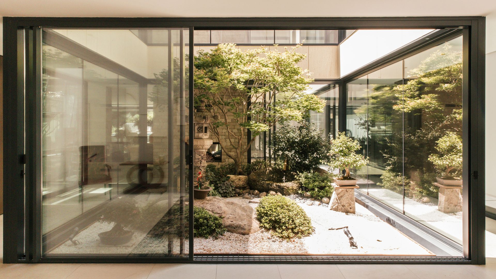 La entrada a la vivienda que recibe con un impresionante jardín japonés interior  
