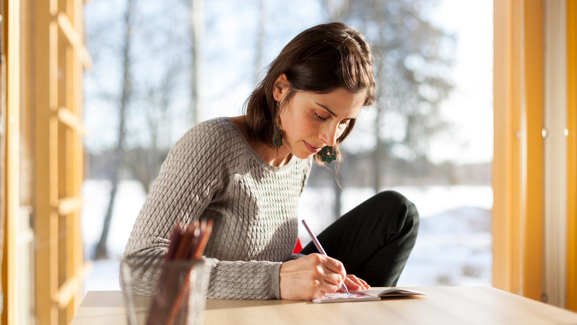 Mujer pintando en un cuaderno en su casa