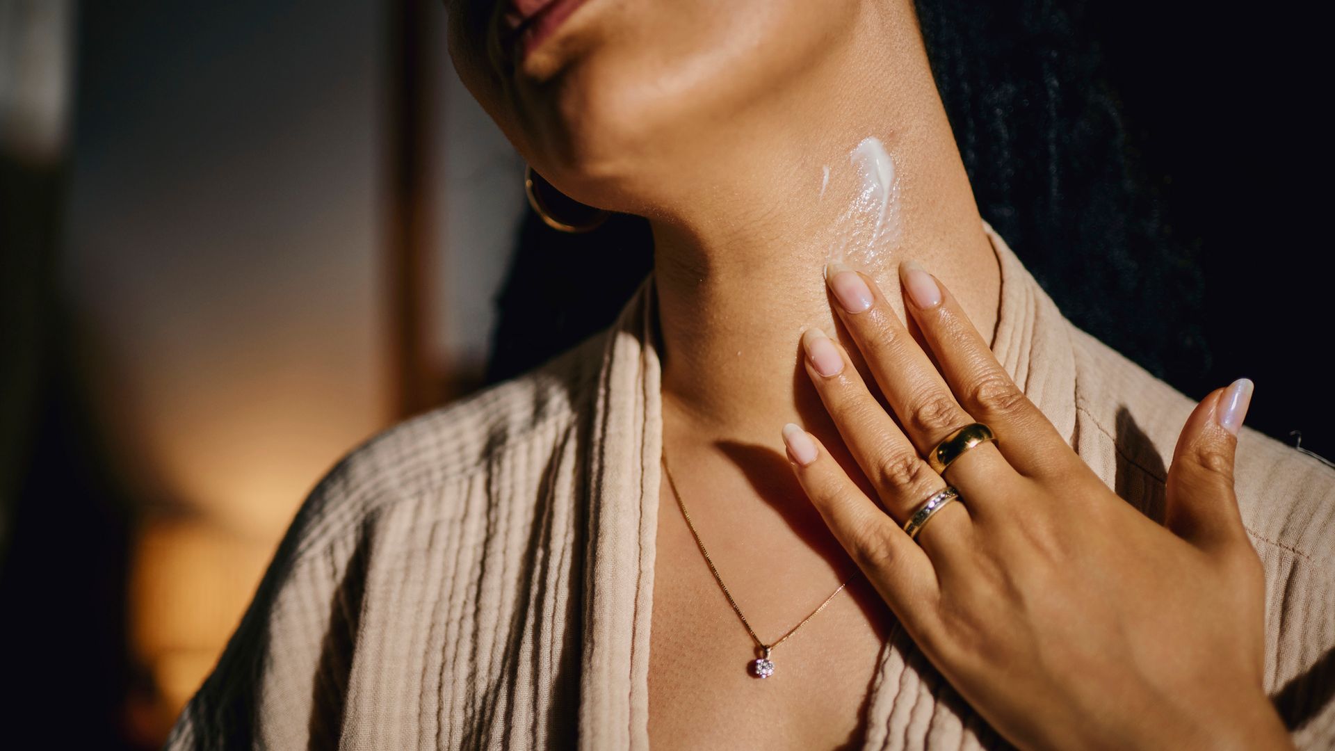 Mujer joven aplicándose crema en el cuello
