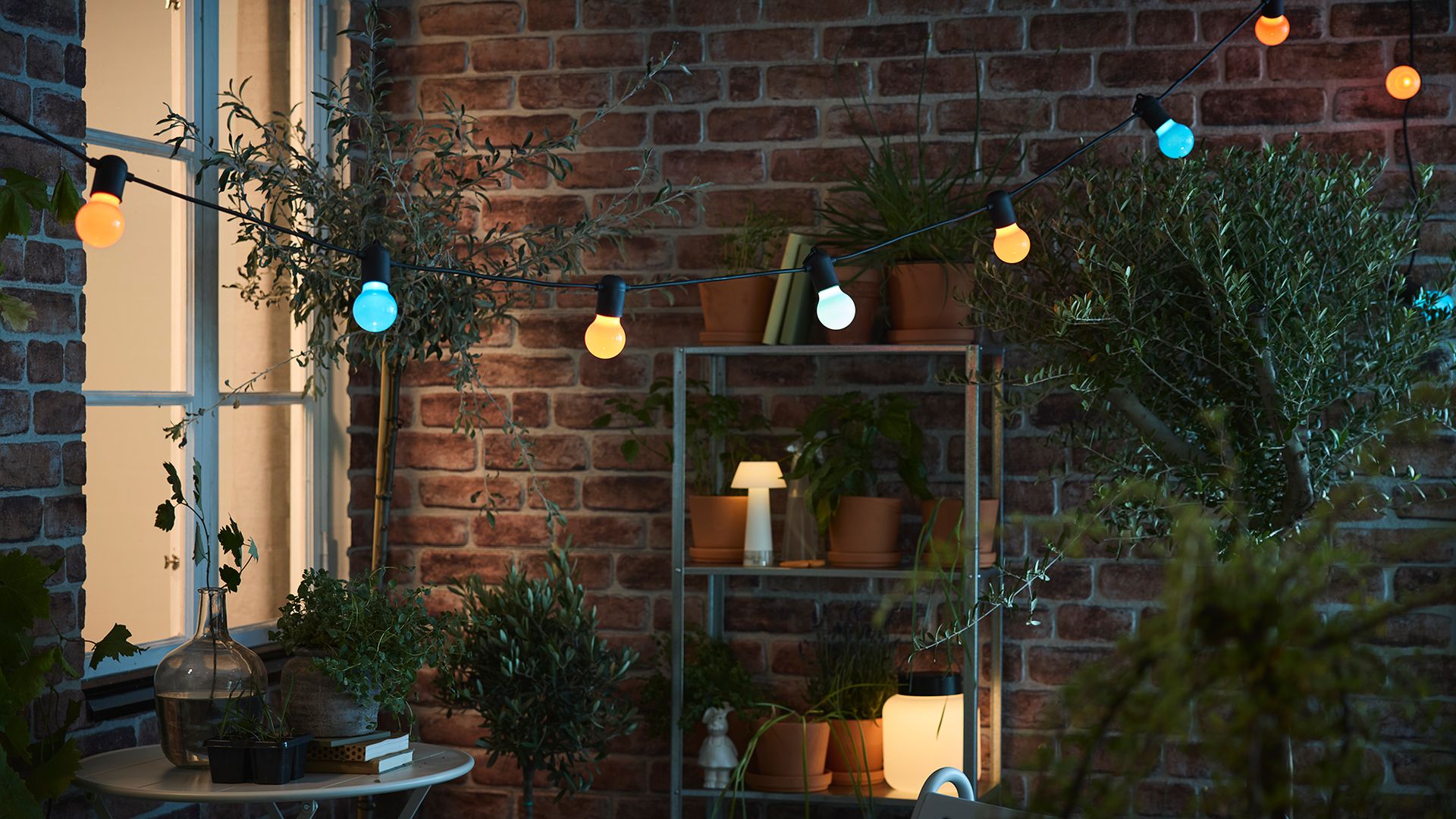 Terraza con muebles IKEA, guirnalda de luces de colores y lámparas de sobremesa 