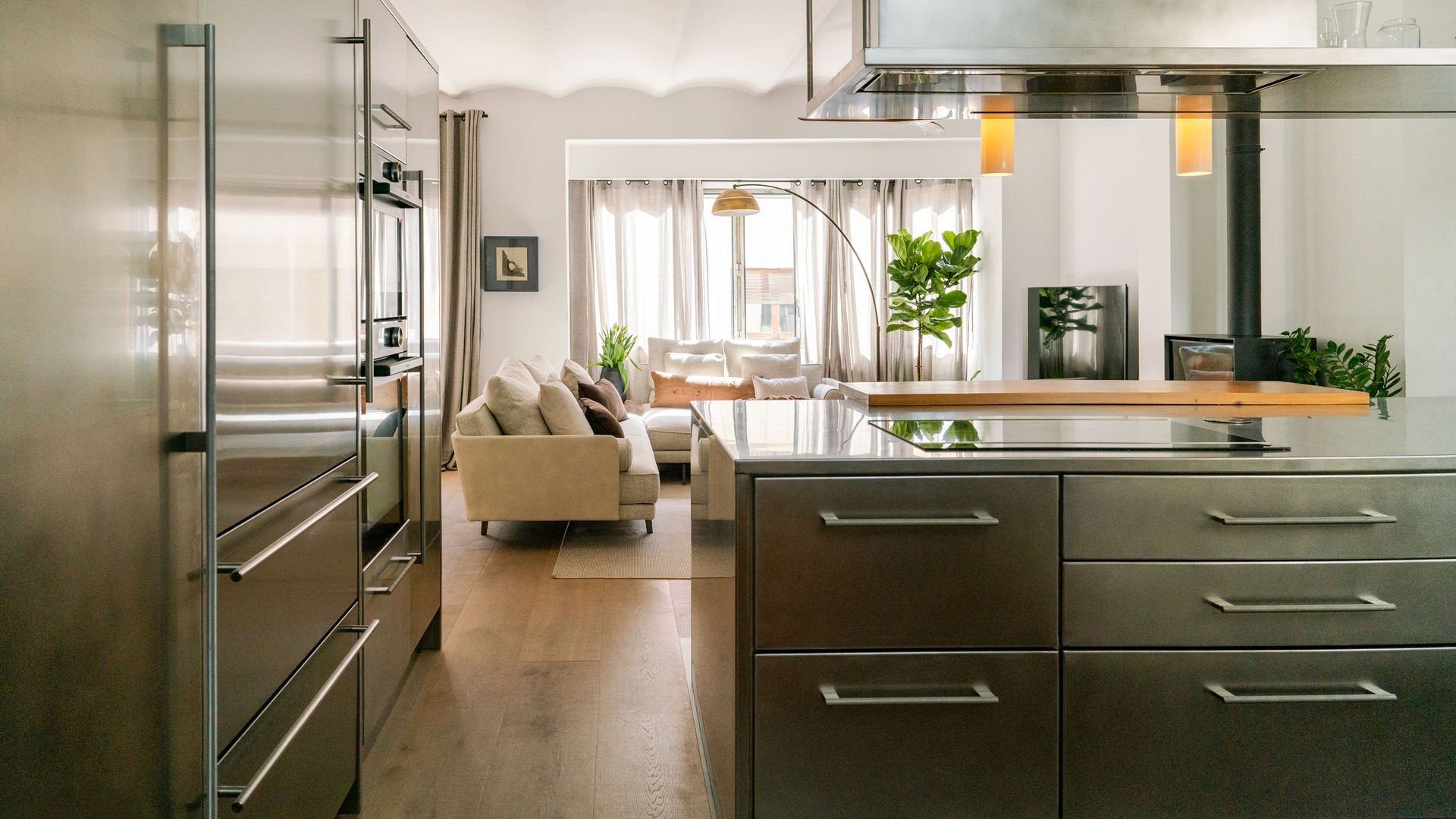 Cocina abierta al salón con muebles, encimera y electrodomésticos metálicos