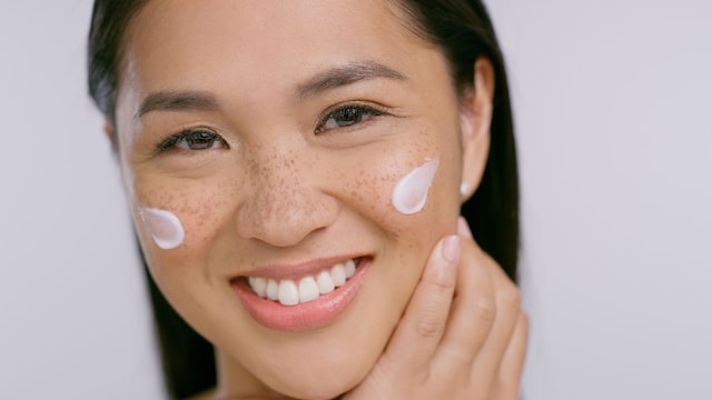 Mujer japonesa en primer plano, sonriente y radiante, tras aplicar su rutina de cuidado facial.