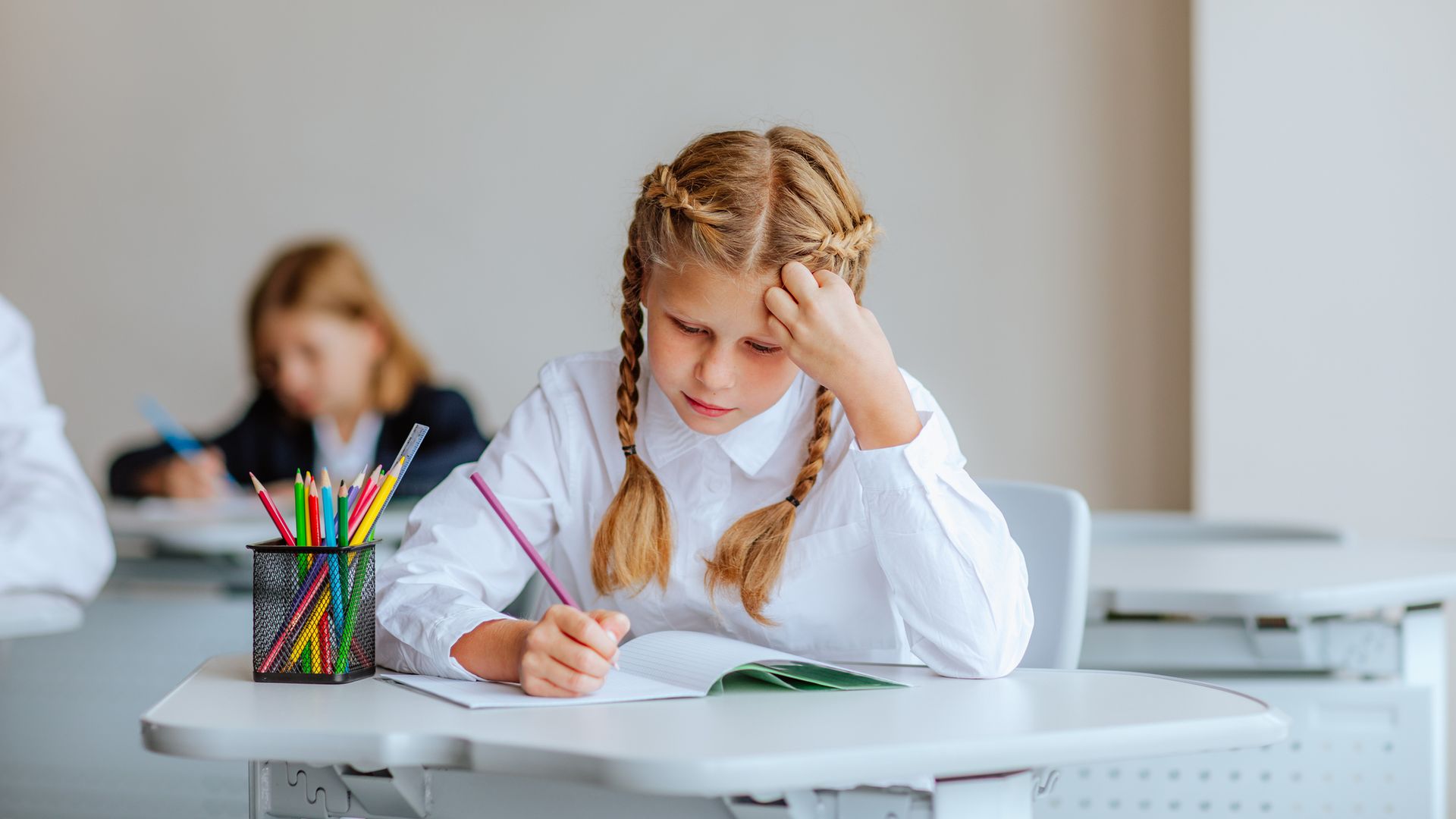 Niña escribiendo en el pupitre del colegio