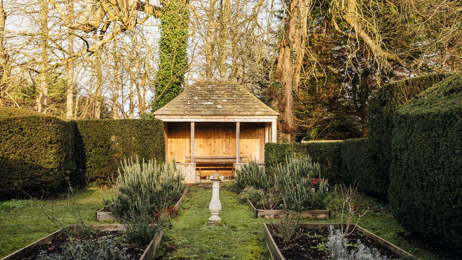 Jardín con estructura de madera, sendero, plantas y fuente