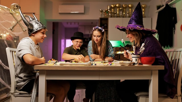 Familia con disfraces de Halloween juega a juegos de mesa
