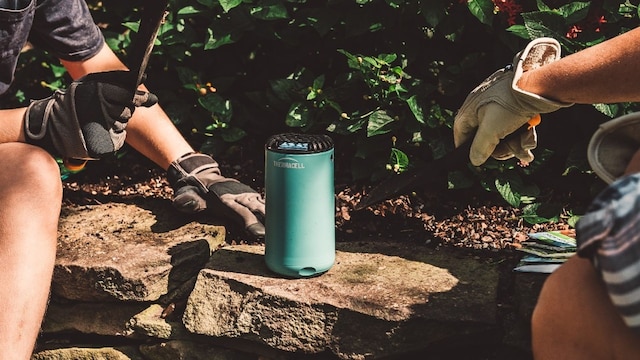 Difusor antimosquitos de Thermacell con dos personas sentadas al lado en un jardín