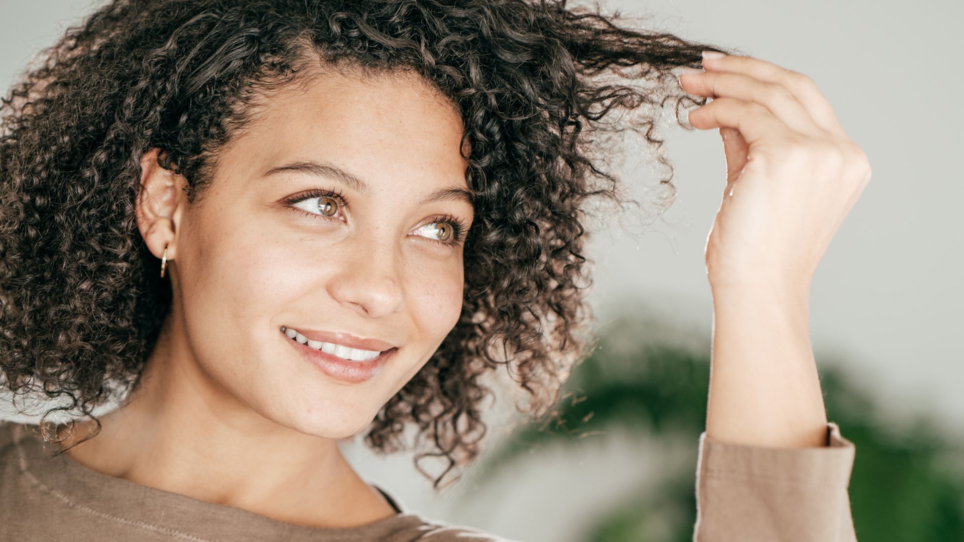 Mujer con pelo rizado mirándose las puntas