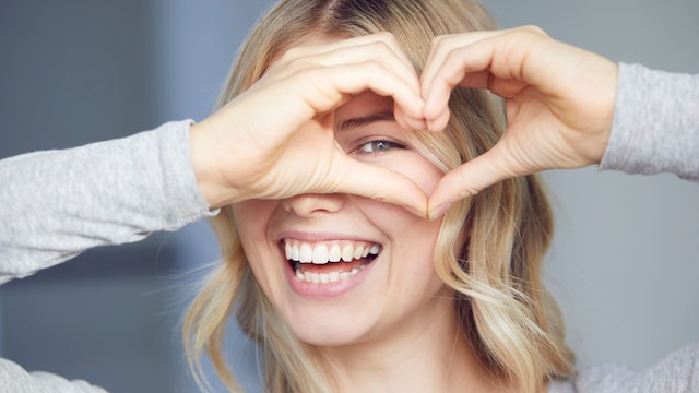 Mujer haciendo un corazón y sonriendo