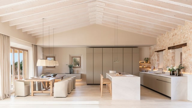 Cocina abierta al comedor, con isla, muebles beiges, vigas de madera en el techo, pared de ladrillos,