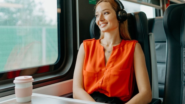 Una chica viajando en un tren con auriculares inalámbricos