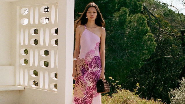 Mujer junto a una piscina con vestido de invitada rosa con estampado floral de Mango