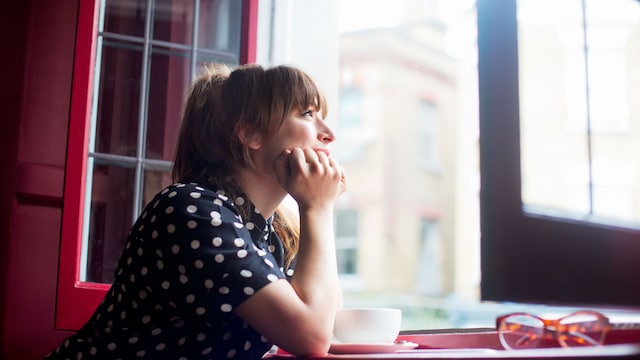 Mujer mirando por la ventana con nostalgia