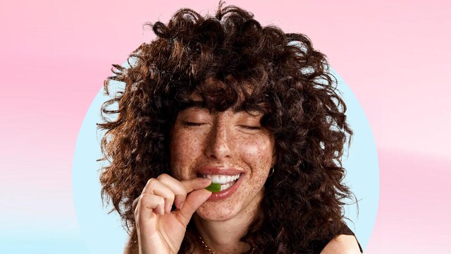 Chica mordiendo una gominola suplemento alimenticio para el cabello de Cocunat Horizontal