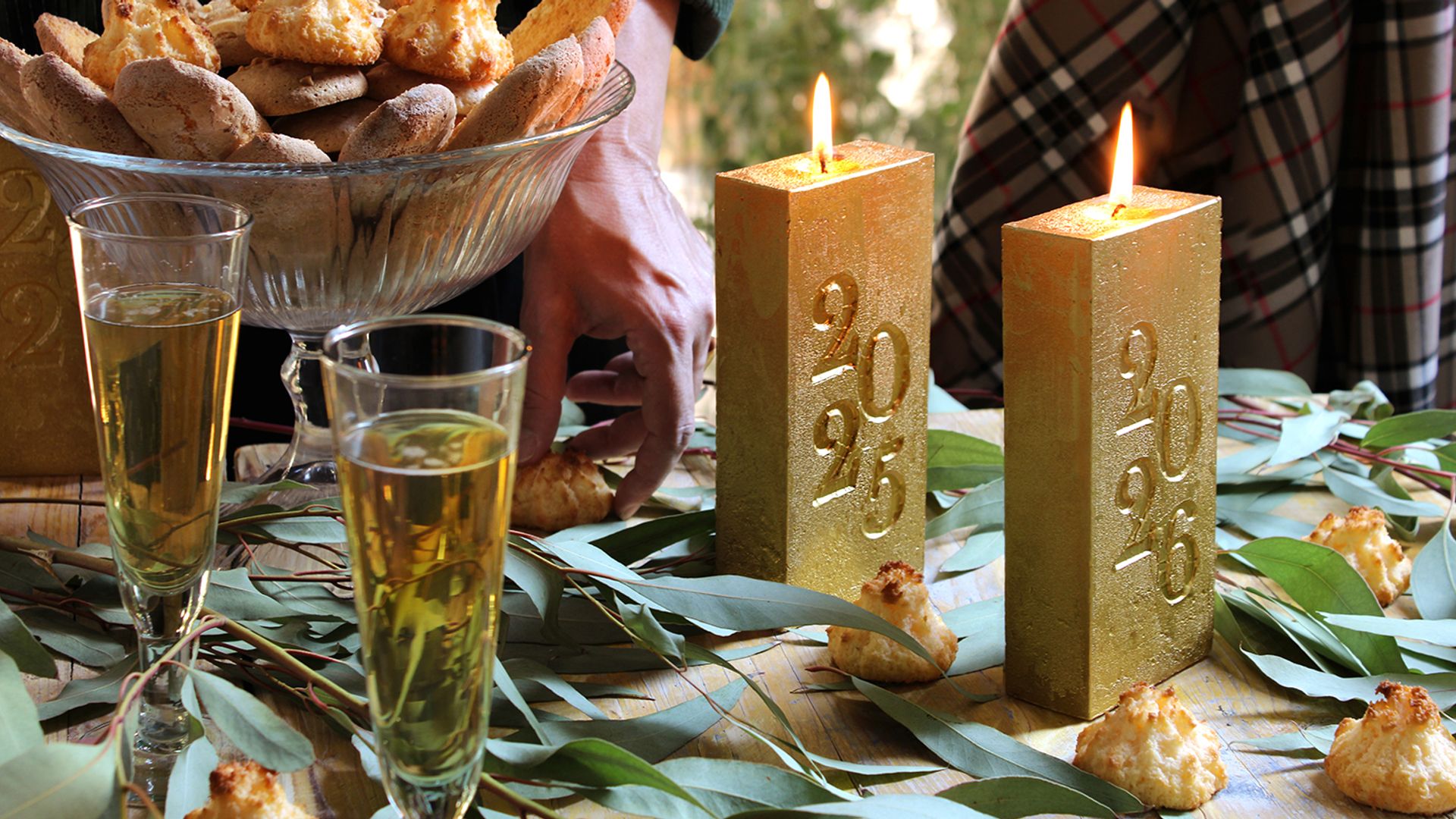 Mesa de Navidad con copas de cava, dulces navideños y velas doradas 