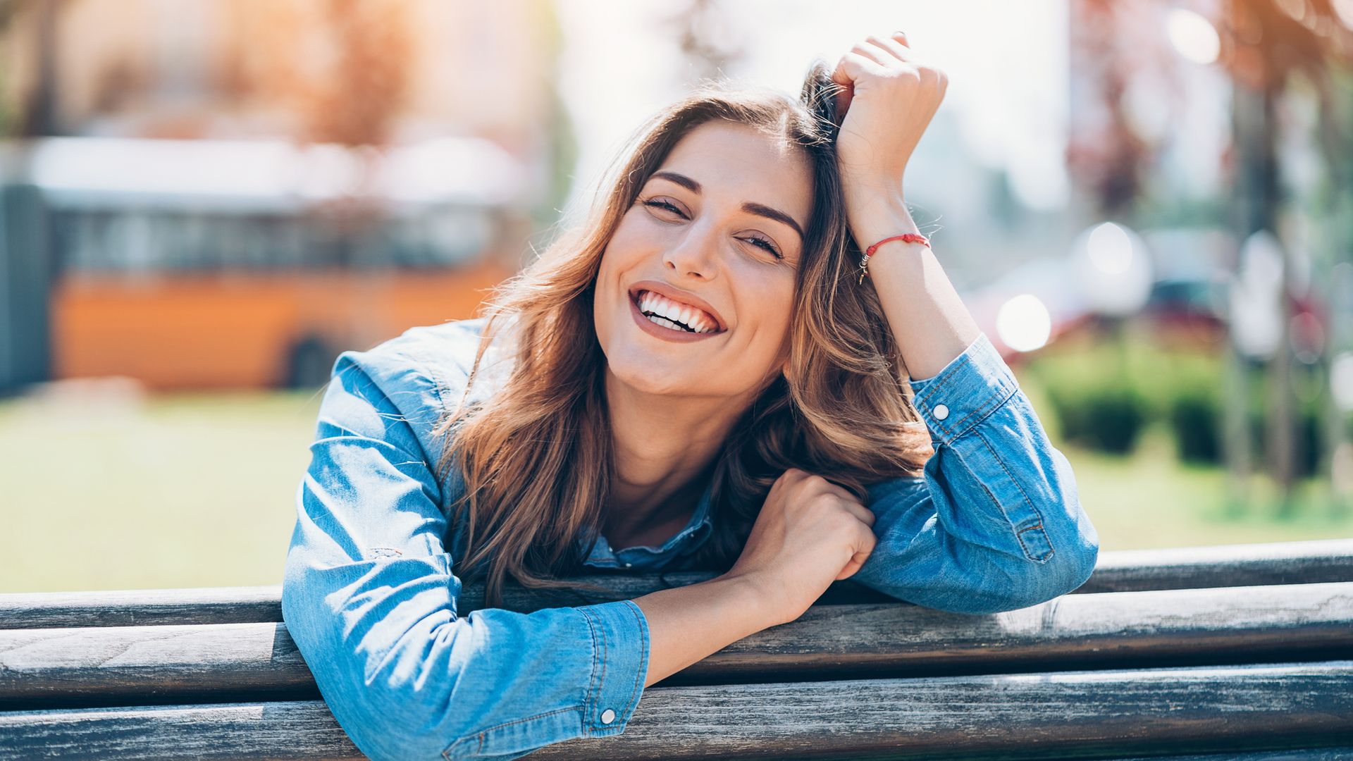 Mujer feliz y riéndose sentada en un banco en el exterior