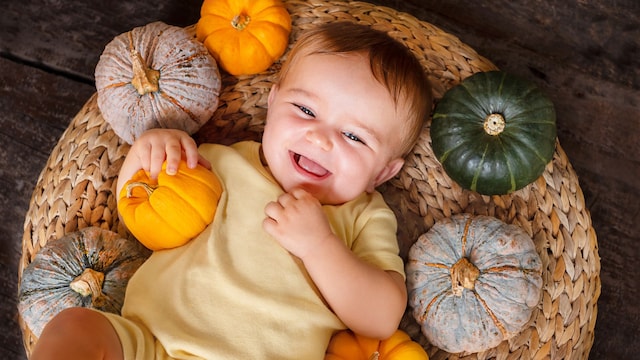 Bebé sonríe entre calabazas