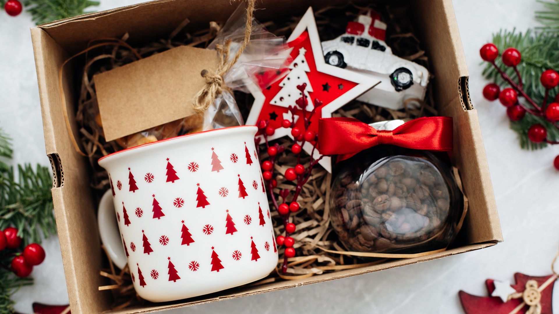 Cesta de Navidad con taza y café, además de adornos navideños en rojo y blanco.