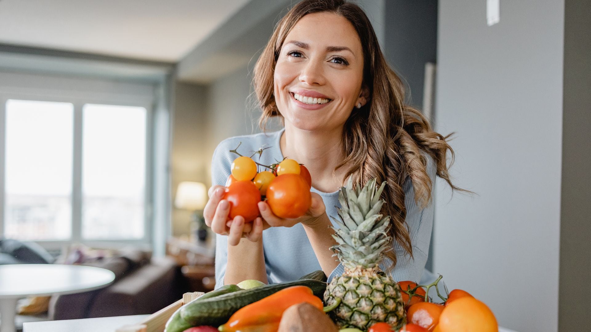 Mujer sonriendo con frutas y hortalizas en una cesta