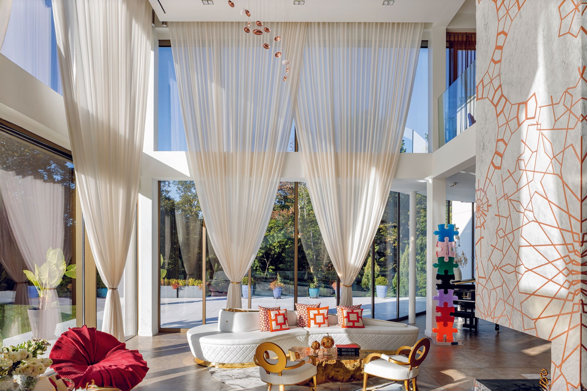 Sala de estar moderna con sofá blanco, cortinas largas, y decoración colorida. Ninguna celebridad identificable presente.